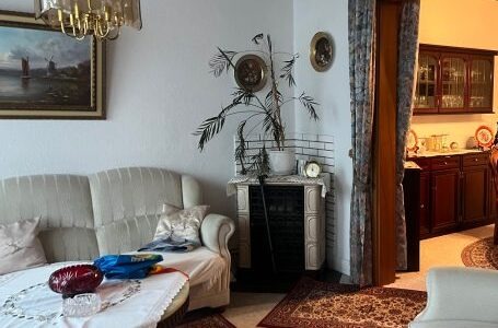 Mitarbeiter tragen ein altes Möbelstück vorsichtig durch ein enges Treppenhaus.